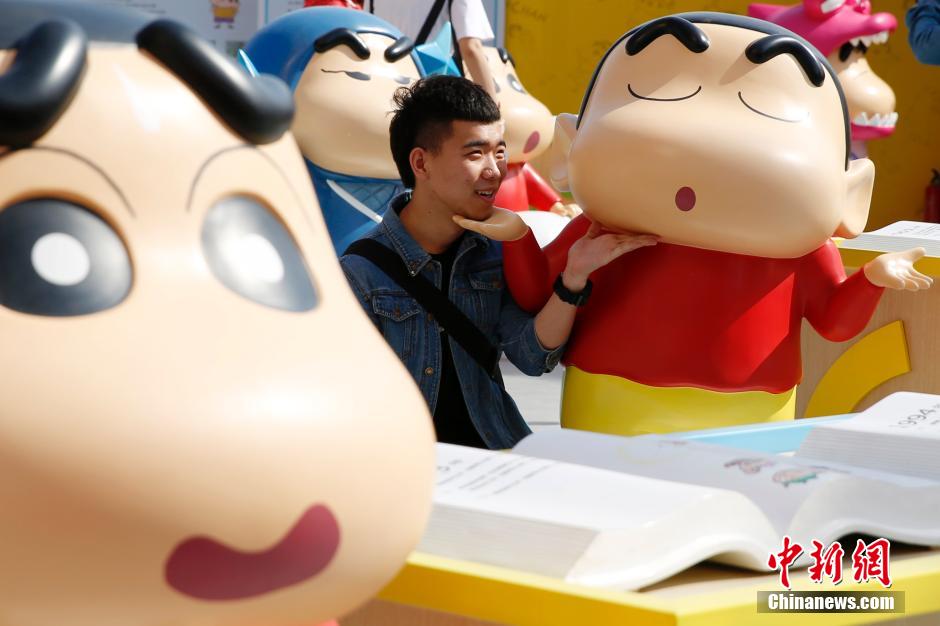 4月22日，游客與蠟筆小新合影?！跋灩P小新25周年紀(jì)念特展”日前在北京開(kāi)展，吸引了不少市民游客。