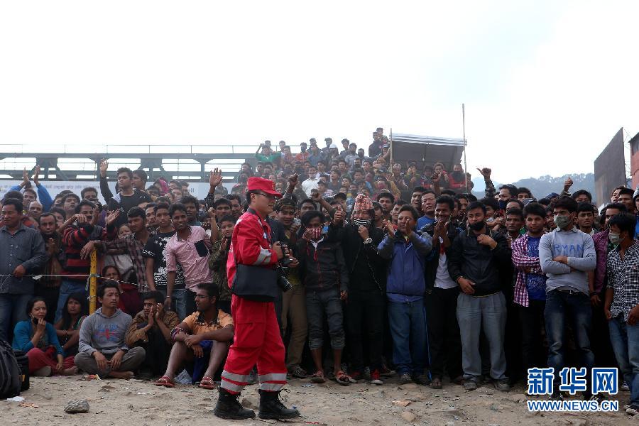 圍觀的尼泊爾民眾在中國國際救援隊(duì)成功搜救出幸存者后向搜救隊(duì)員歡呼致意。