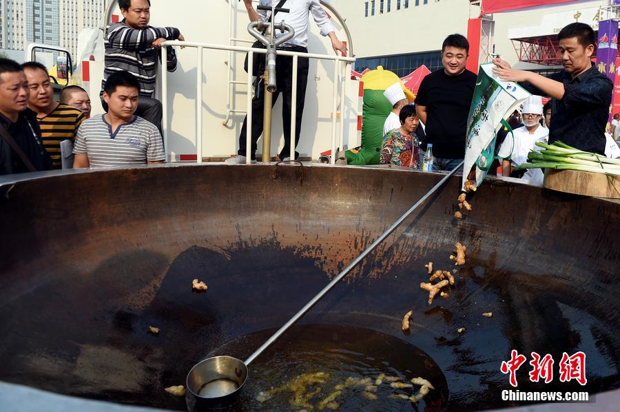 工作人員向大鍋內(nèi)加入油和姜等烹飪調(diào)料。 圖片來源：CFP視覺中國