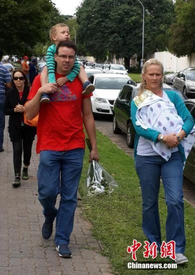 圖為一個(gè)白人家庭，由父母帶著孩子到曼德拉家門外悼念。中新社發(fā) 宋方燦 攝