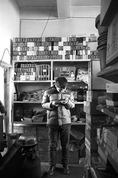 1月21日，周瑋在自家的超市里玩計(jì)算器。