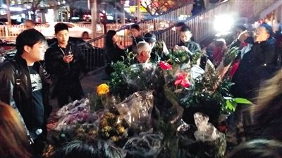 昨晚7時許，三里屯太古里西邊附近一過街天橋旁邊，聞訊而至的網(wǎng)友圍住了賣花老人，爭相買花。 網(wǎng)友“行者橙子”供圖