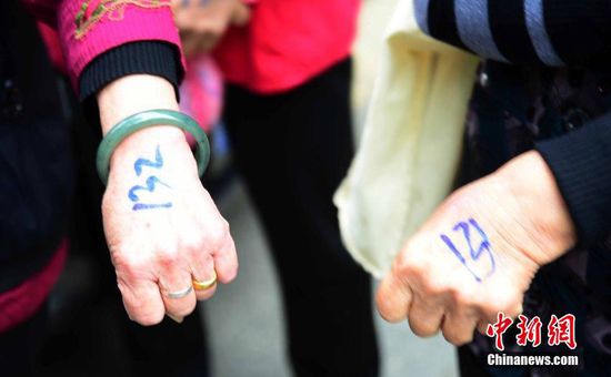 圖為10月28日，在江西九江市一家羊絨皮草服裝服飾博覽會現(xiàn)場，老人們正在頂著寒風排隊等待領(lǐng)取10元代金劵。