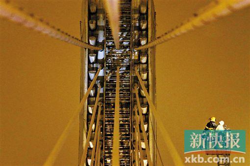 截至今日零時(shí)，男子仍未有下橋舉動(dòng)。圖為公安和消防人員乘消防云梯在高空上和男子交談。